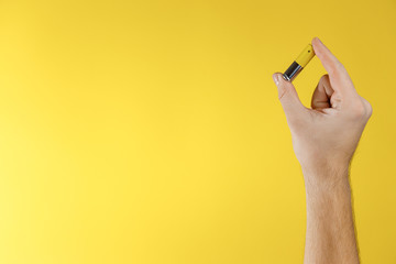 Male hand hold gray-yellow alkaline AA batterie on a yellow background. Recycling of rechargeable NiMH batteries. The most popular size of accumulators. Copy space.
