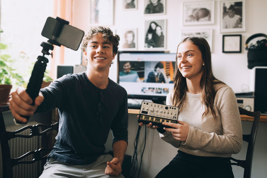 Teenage boy taking selfie with friend holding sound mixer at home