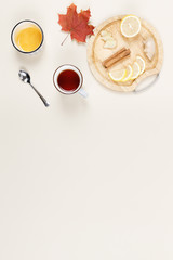 Lemon, ginger and cinnamon sticks on wooden plate. Bowl of honey, cup of tea and maple leaf nearby. Flu season. Natural remedies. Treatment of cold and viruses at home. Healthcare concept. Copy space.