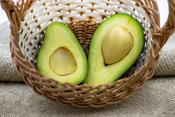 Two halves of avocado in a wicker basket on the background of burlap_