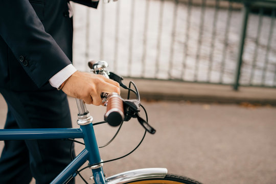 Midsection of businessman with bicycle on bridge in city