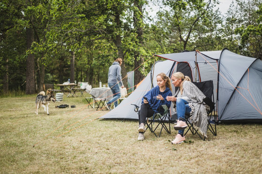 Mother and daughter having coffee while using mobile phone at campsite