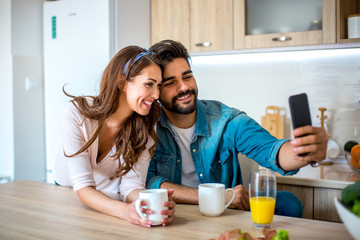 Young attractive Caucasian couple, posing for a selfie while they are having a cup of coffee in the...