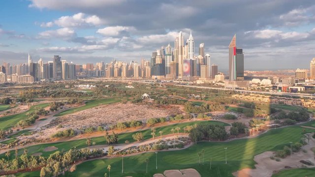 Dubai Marina with JLT skyscrapers and golf course morning timelapse, Dubai, United Arab Emirates. Aerial view from Greens district. Green lawn and cloudy sky