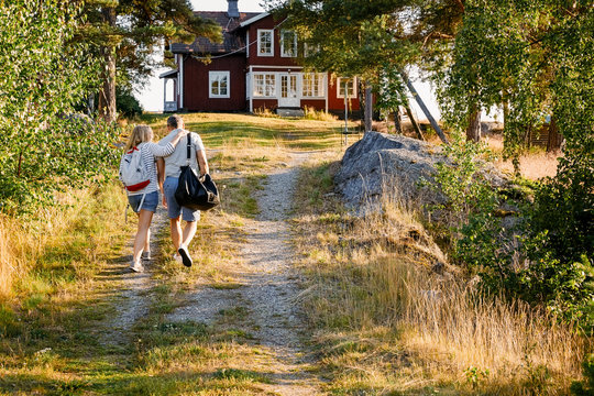 Male and female partners walking on pathway towards house during summer vacation