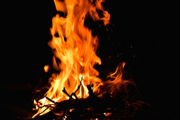 Obraz premium in the photo of a dark night, a yellow-red flame burns, firewood is visible from below
