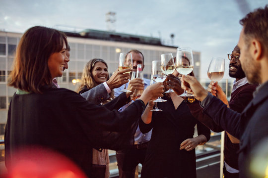 Business colleagues toasting wineglasses while celebrating office party on terrace