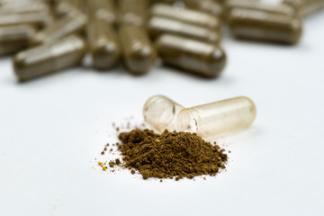 Capsule with braun powder. Background from heap of medicine pills.