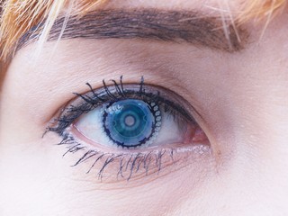 A beautiful eye of a young lady with advanced visual user interface technology blue contact lens, black eyelash and eyebrow, and blond hair