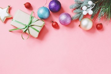 Wrapped gift box, red, blue, purple balls, spruce branch. Christmas and New Year ornament on a pink background