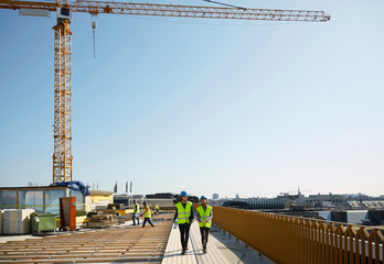 Female coworkers walking at construction site against clear sky