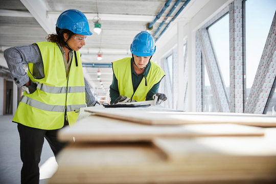Architects talking over blueprint at construction site