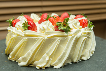 Side view of creamy white chocolate cake with strawberry slices. Sweet dessert about ardoia. Sweet concept for celebrations. Focus selective.