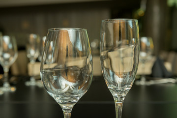 Side view of two different empty glass cups on a black table. Empty wine glass on a gray background. 
