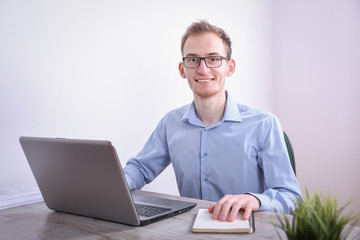 Portrait of young  business man sitting at his desk desktop laptop technology in the office.Internet marketing, finance, business concept
