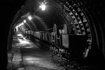 An old, hollow underground tunnel in a closed coal mine. - obrazy, fototapety, plakaty