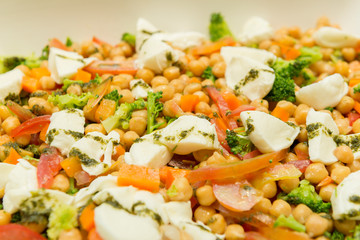 Closeup of Chickpea Salad with Tomatoes, Brocolis and Buffalo Cheese on a Foursquare Ceramic Platter on Wooden Table. Healthy and tasty food. Selective focus.
