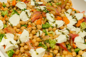 Closeup of Chickpea Salad with Tomatoes, Brocolis and Buffalo Cheese on a Foursquare Ceramic Platter on Wooden Table. Healthy and tasty food. Selective focus.
