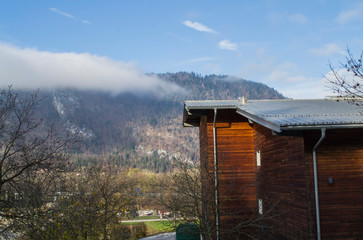 wooden house by the mountain with clouds