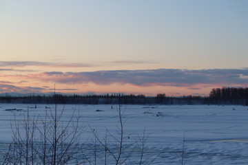 Sunrise colored sky over frozen river