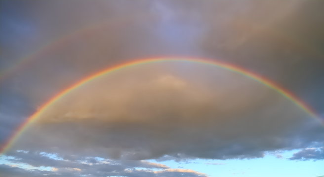 Full double rainbow in the sky against the background of clouds