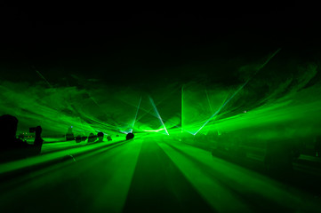 People bathed in fog and laser light, laser show.