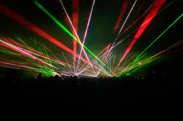 People bathed in fog and laser light, laser show.