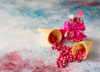 Heart shaped pink sugar candies and waffle cones on pink and aqua colors background. Valentine's Day concept. Copy space