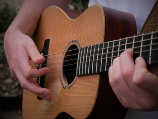 Acoustic guitar playing musician close up of guitar, strings, fretboard and hands