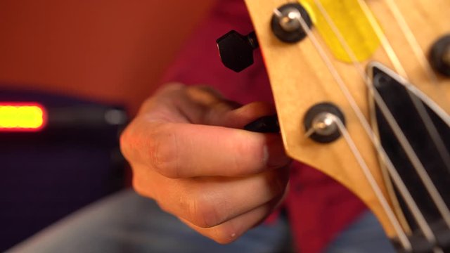 Close up of handement of man tuning his guitar
