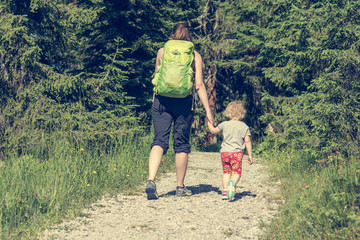 Mother and daughter hiking on a forest path.