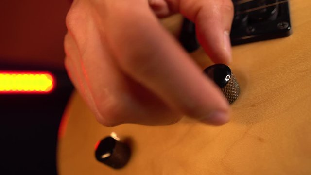 Close up professional guitarist tuning electric guitar at studio