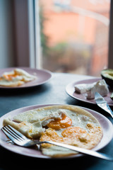 Vertical frame breakfast consisting of scrambled eggs for two persons, standing on a table near the window. Selective focus. Back light