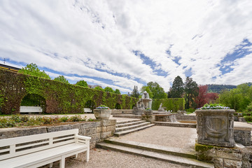Beautiful public park in a European city with an antique fountain and green bushes