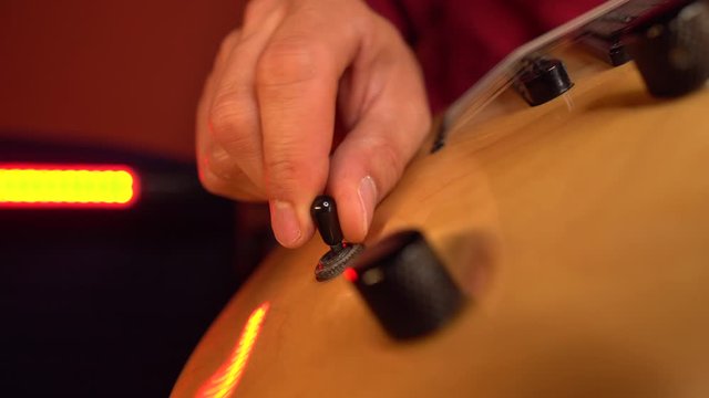 Close up of guitarist hand is tuning guitar