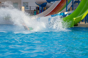 Obraz premium Happy cheerful people splashing water on water slide at aqua park..
