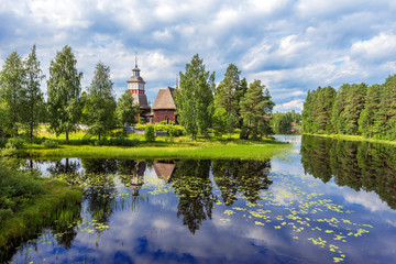 Fototapeta na wymiar Old wooden church of Petajavesi village is a part of natural environment of lake and forests. Jyvaskyla region in Central Finland.