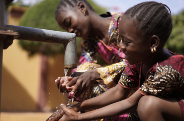 Two Gorgeous African Children Girls Drinking Freshwater in Bamako, Mali