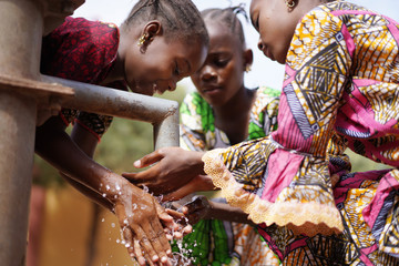 Gorgeous African Girls Washing Hands under Water Tap Outdoors - obrazy, fototapety, plakaty