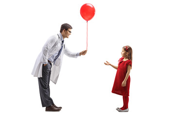 Male doctor giving a red balloon to a girl
