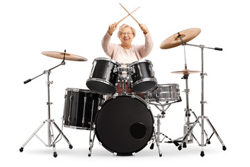 Fototapeta premium Senior woman holding crossed drumsticks with a set of drums