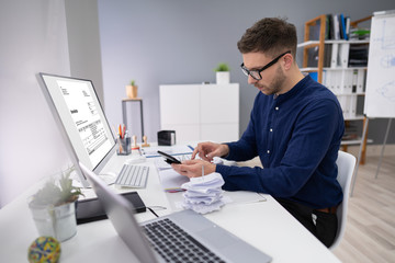 Businessman Calculating Invoice In Office
