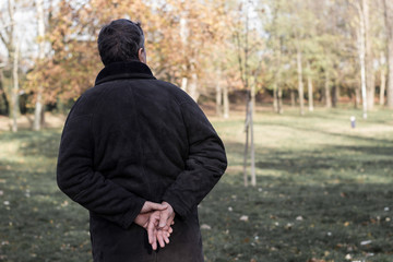 Fototapeta premium Senior man walking and relaxing in park. Walking away, relaxing, rear view