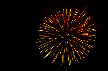 Yellow and red fireworks in the shape sphere on the right side on a black background.