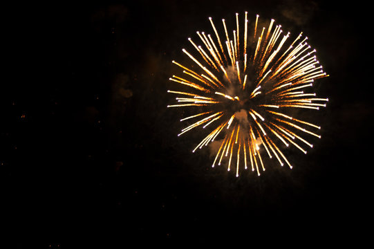 White and yellow fireworks in the shape sphere on the right side on a black background.