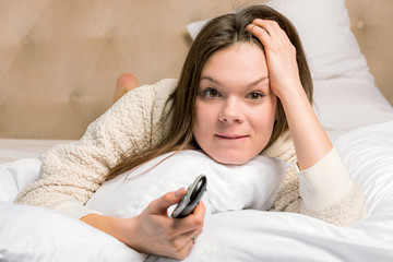 Young woman on the bed holding remote control