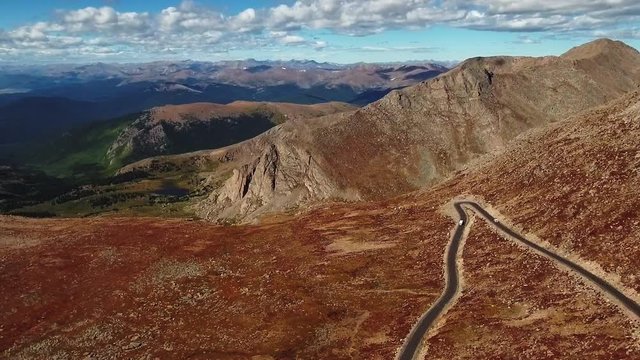 Aerial shot of winding road on top of the plateau of Mount Evans, Colorado, USA with valley and mountain range panorama in the background