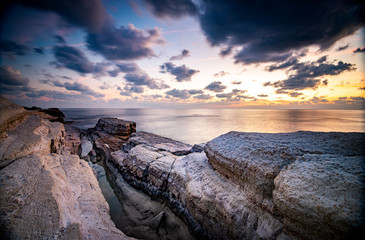 Rocky seashore seascape with dramatic and beautiful sunset at sea caves coastal area  in Paphos, Cyprus