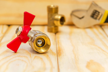 Ball water valve for plumbing with red handle on wooden boards