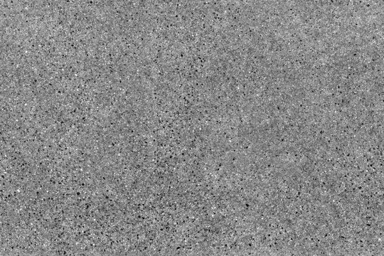 Seamless asphalt road background. Grainy floor texture with gravel particles, small stones, black, gray and white grains. Close up, top view. Gray asphalt pattern. Bitumen road texture